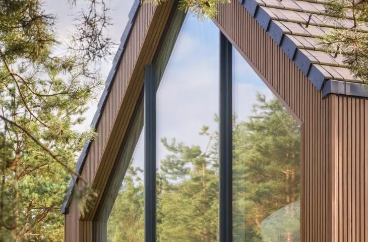 The large-format glazing at the top of the floor frames the tops of the pine trees