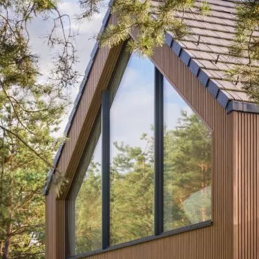 The large-format glazing at the top of the floor frames the tops of the pine trees