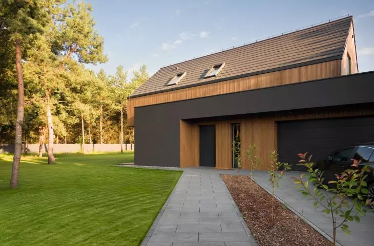 The entrance area is integrated into the building's graphite-colored base and accented with wood