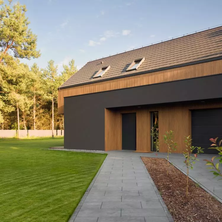 The entrance area is integrated into the building's graphite-colored base and accented with wood