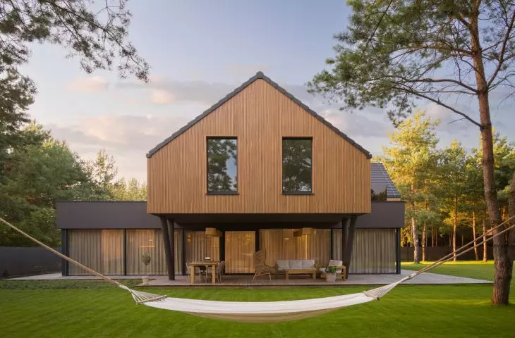 The wooden upper level hovers above the glass-enclosed ground floor and the covered terrace