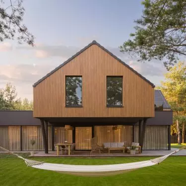 The wooden upper level hovers above the glass-enclosed ground floor and the covered terrace