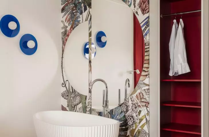 The freestanding bathtub was placed in the room against a backdrop of floral wallpaper, and the mirror made the space appear larger