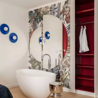 The freestanding bathtub was placed in the room against a backdrop of floral wallpaper, and the mirror made the space appear larger