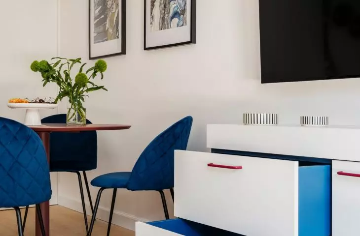 The cobalt-blue chairs and lamp liven up the bright living area, and the vivid blue also appears inside the drawers