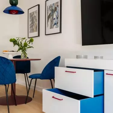 The cobalt-blue chairs and lamp liven up the bright living area, and the vivid blue also appears inside the drawers