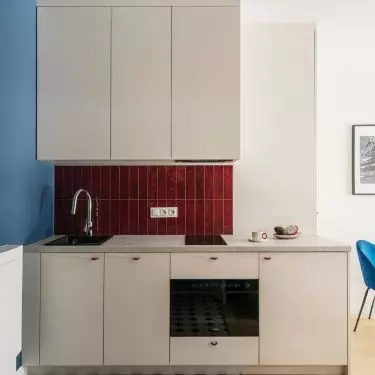 The kitchenette features a cobalt-blue wall that extends up to the ceiling and burgundy tiles above the countertop