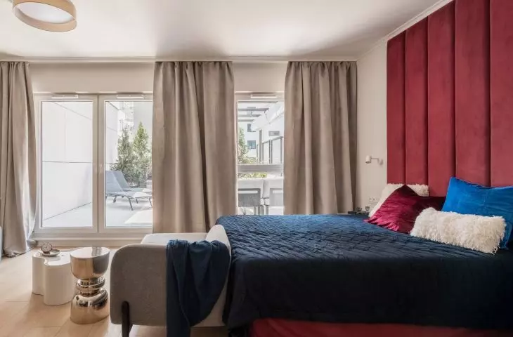 The bed has been incorporated into the open space, and the ruby-red headboard and cobalt-blue textiles echo the design’s main colors