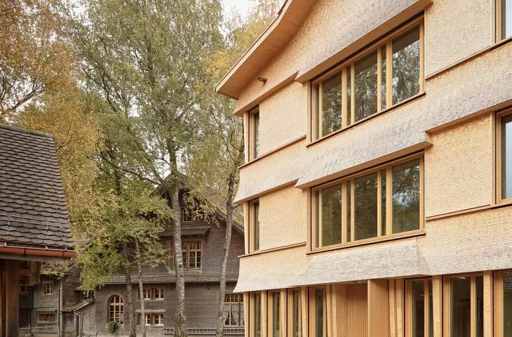 The shingle-clad facade and sloping roof of the new section echo the historic buildings in the complex