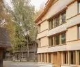 The shingle-clad facade and sloping roof of the new section echo the historic buildings in the complex