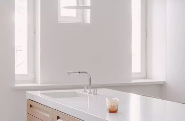 Drewniane fronty szafek wyspy ocieplają jasną kuchnię