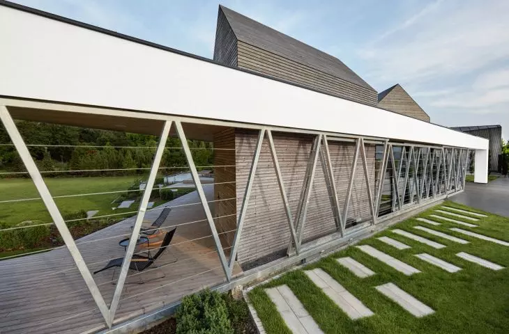 white frames surrounding the house on the side of the plot act as a terrace canopy