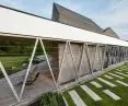 white frames surrounding the house on the side of the plot act as a terrace canopy