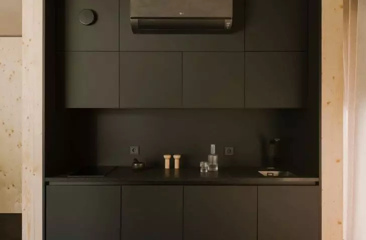 minimalistyczna kuchnia w ciemnym kolorze kontrastuje z jasną sklejką świerkową