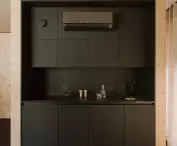 minimalistyczna kuchnia w ciemnym kolorze kontrastuje z jasną sklejką świerkową