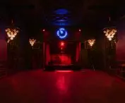 ponad sceną wisi neon wskazujący godzinę 23:55