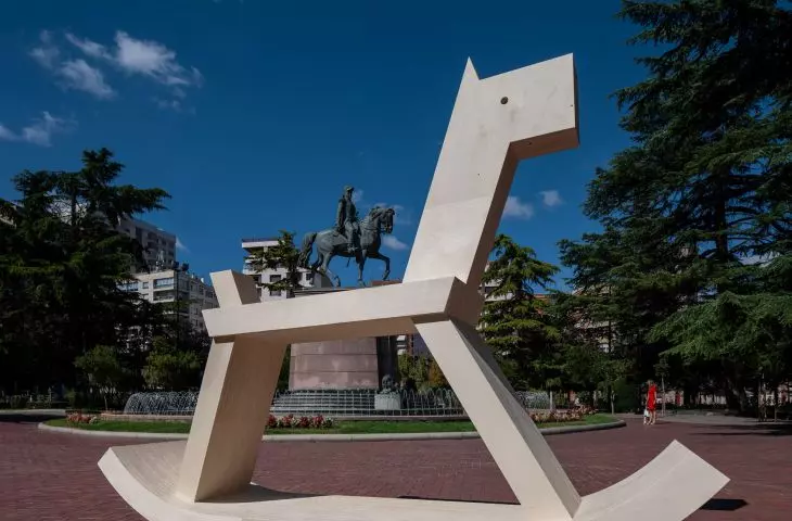 The scaled-down rocking horse alludes to the traditional horse statue