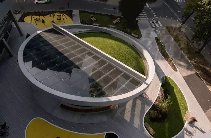 Concrete ring surrounds glass canopy and green elevation