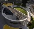 betonowy ring otacza szklane zadaszenie i zielone wzniesienie