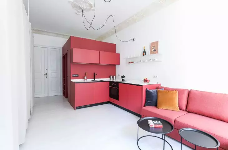 kubik i sofa w kolorze malinowym w kawalerce M4