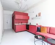 kubik i sofa w kolorze malinowym w kawalerce M4