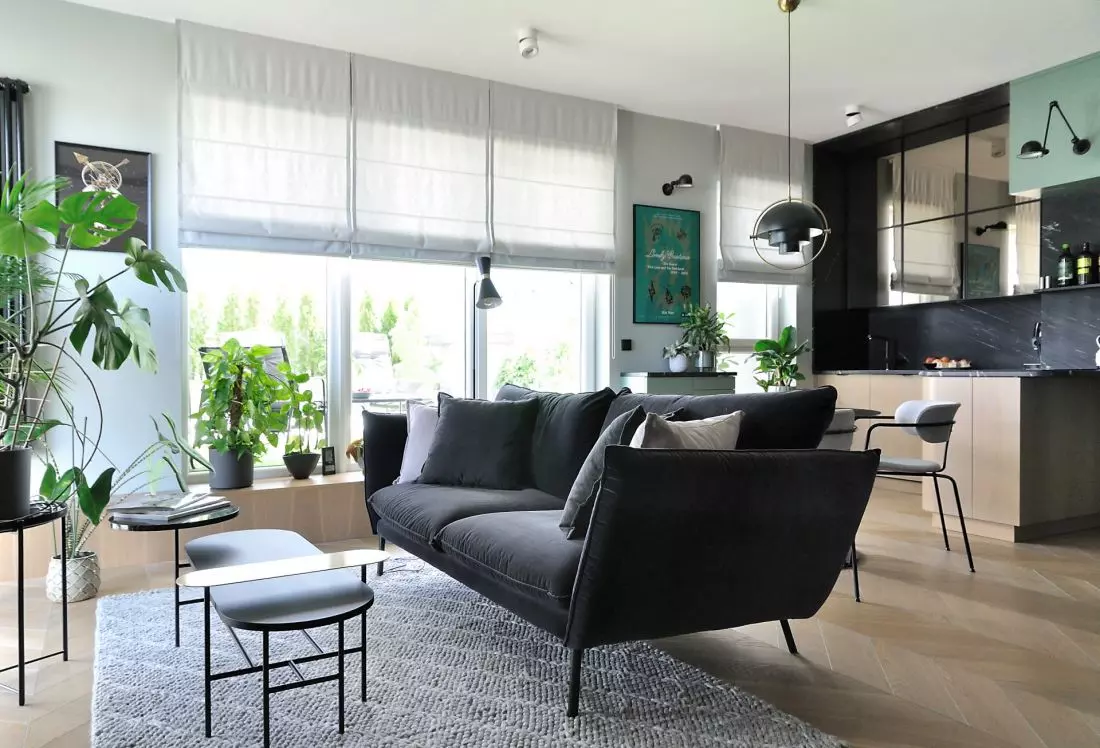 salon z otwartą
kuchnią, na pierwszym planie czarna sofa