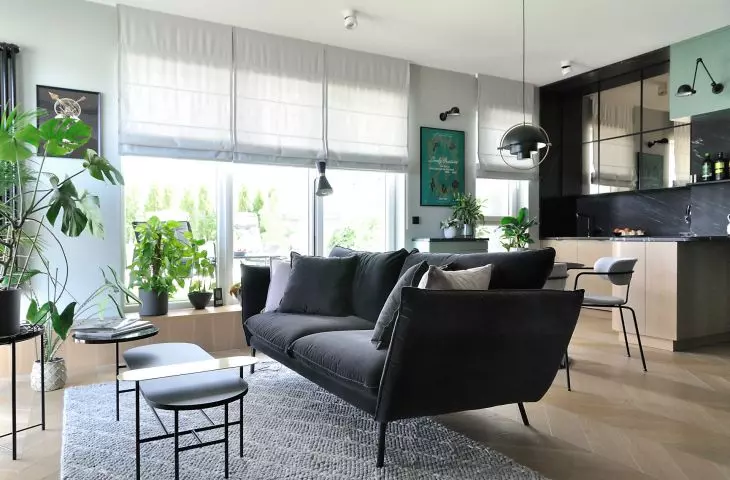 Living room with open kitchen, black sofa in the foreground