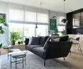 Living room with open kitchen, black sofa in the foreground