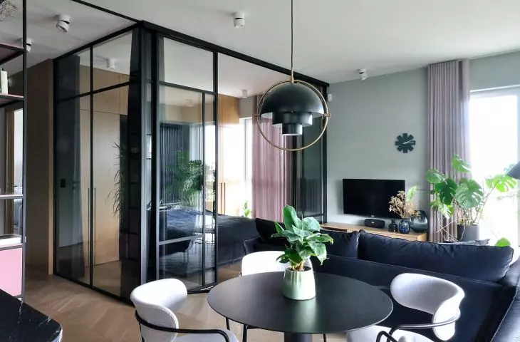 The bedroom is separated from the living room by glass walls