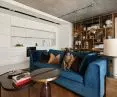 The white kitchen contrasts with the warm colors of the living room