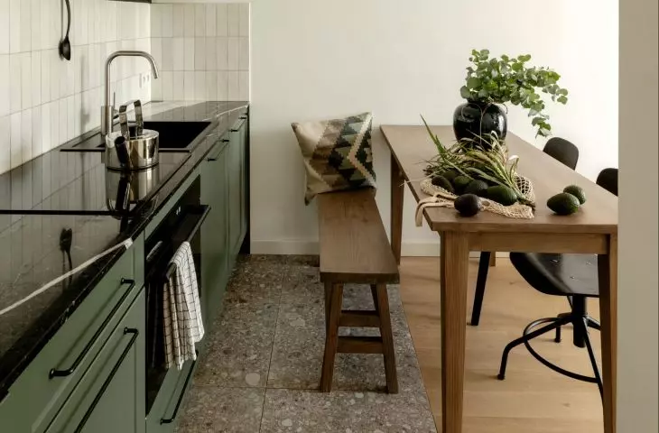 dark green, low kitchen cabinets are juxtaposed with narrow, glossy tiles on the wall