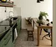 dark green, low kitchen cabinets are juxtaposed with narrow, glossy tiles on the wall