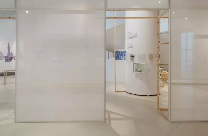 of the non-existent street is reminded by the minimalist wooden structure with white canvas dividing the exhibition