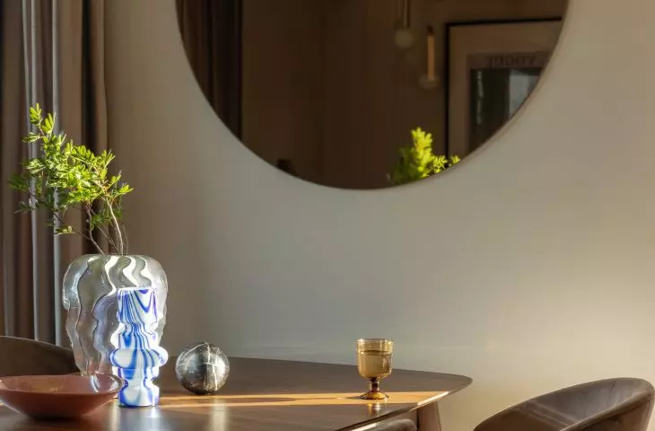 On the wall of the living room hangs a large round mirror