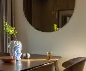 Na ścianie salonu wisi duże, okrągłe lustro