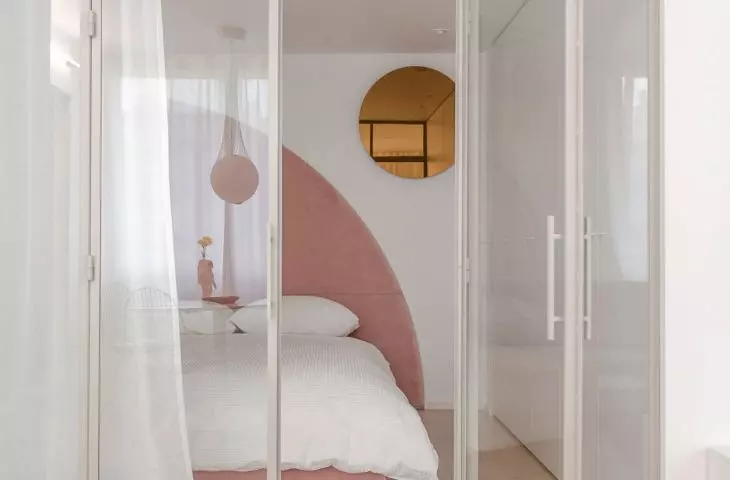The bedroom is separated from the living room by glass walls