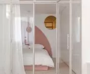 The bedroom is separated from the living room by glass walls