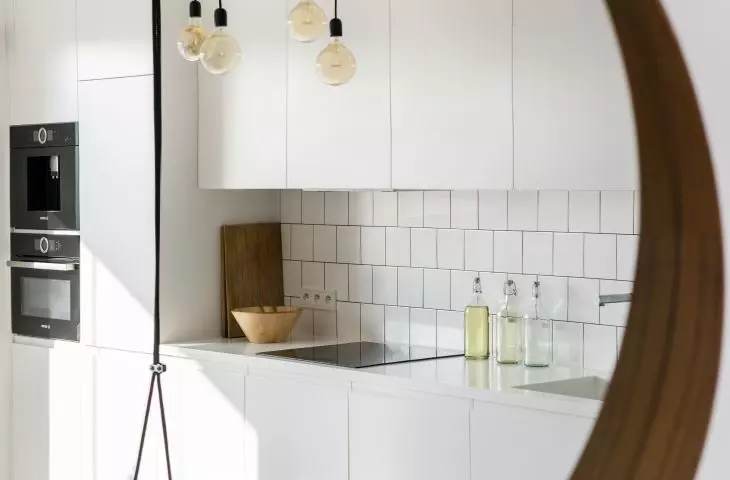 W lustrze odbija się biała kuchnia