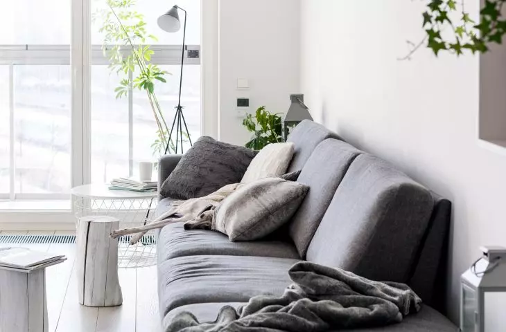 Szara sofa odcina się na białym tle ścian