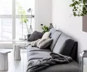 Szara sofa odcina się na białym tle ścian