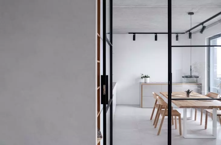 The kitchen is separated from the living room by a glazed loft door, in black steel frames 