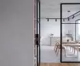 The kitchen is separated from the living room by a glazed loft door, in black steel frames 