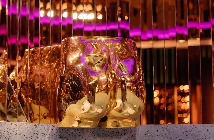złota pupa otoczona lustrami, pełniąca funkcję suszarki do rąk w surrealistycznej toalecie