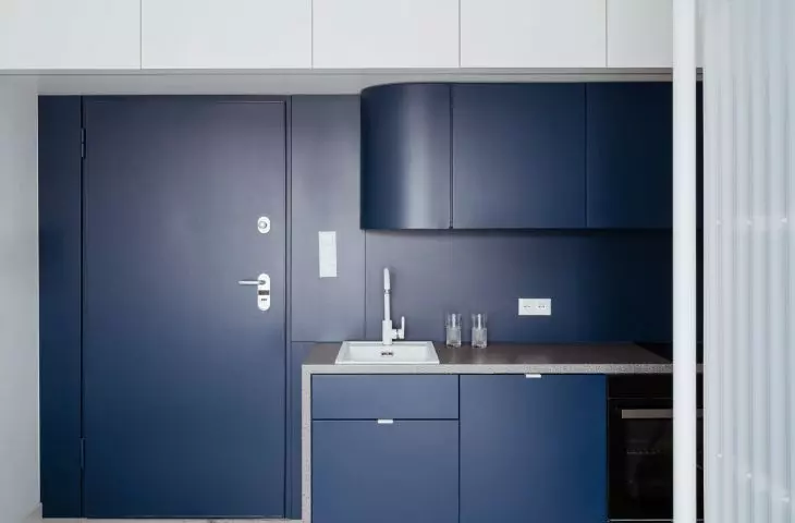 The navy blue color on the front door and in the kitchen contrasts with the bright interior