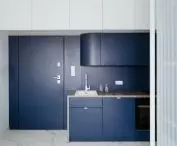 The navy blue color on the front door and in the kitchen contrasts with the bright interior