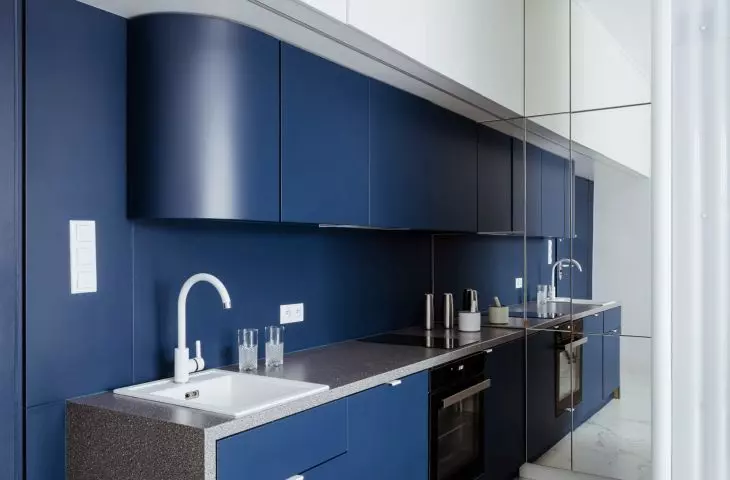 The interior is optically enlarged by a wall of mirrors in the kitchen