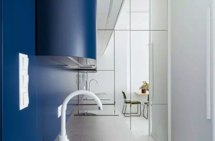 The interior is optically enlarged by a wall of mirrors in the kitchen