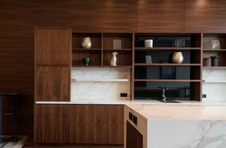 Two impressive bookcases made of Calacatta Polished model were placed against the dark wood panels