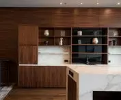 Na tle paneli z ciemnego drewna umieszczono dwa imponujące regały wykonane z modelu Calacatta Polished