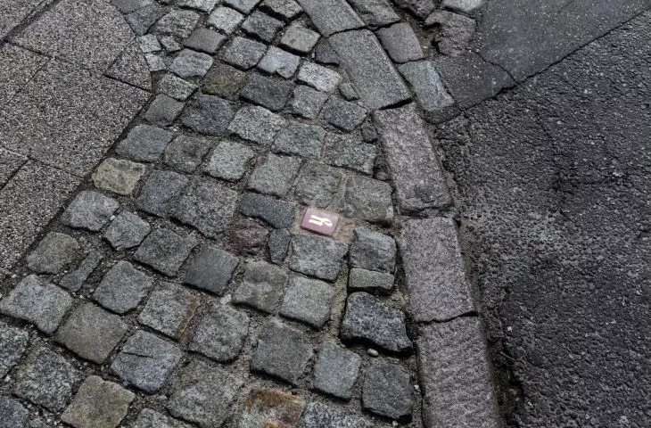 Kostka z „Alfabetu gdańskiego” w chodniku miejskim 